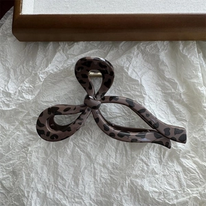 Detail view of leopard print hair claw clip with bow design and gold metal spring