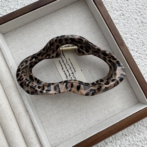 Close-up of wavy leopard print hair claw clip with gold metal spring and vintage texture