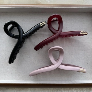 Close-up of matte cloud hair claws in black, burgundy and pink with gold lettering