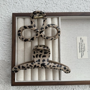 Pinces à cheveux élégantes beige à motif léopard sur un plateau à bijoux en bois chic