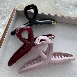 Close-up of three large matte and glossy hair claws in black, wine red, and lilac