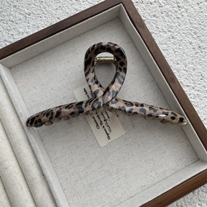 Close-up of vintage brown leopard print hair claw clip with golden metal spring detail