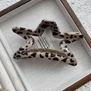 Détail de la pince à cheveux étoile à motif léopard en résine beige avec fini poli