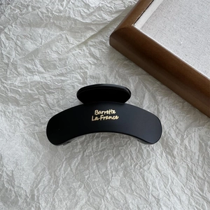 Close-up of a matte black shark hair claw with gold Barrette La France lettering