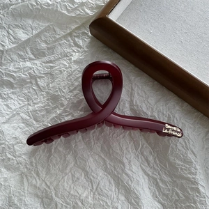 Macro detail of matte burgundy hair claw clip with golden Barrette La France lettering