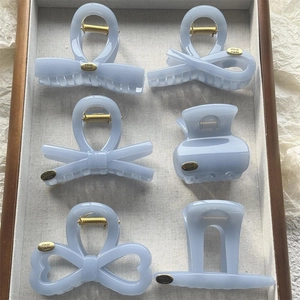 Detail view of light blue hair claw clips set with handmade gold metal tags in a tray