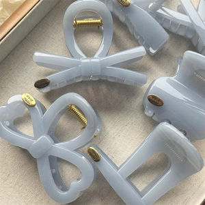 Minimalist light blue hair claw clips in various shapes with gold handmade metal labels