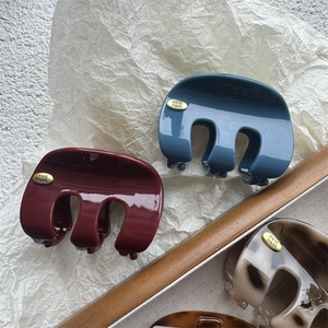 Détail des étiquettes en métal sur les pinces à cheveux en bleu marine, bordeaux et marbre