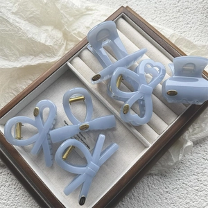 Detail of light blue bow hair clips with gold springs and handmade labels on a tray