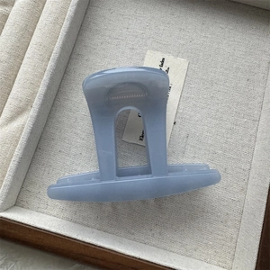 Gros plan d'une pince à cheveux bleu sel de mer au fini mat sur tissu beige