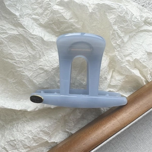 Close-up of light blue acrylic hair claw clip with golden Hand Made metal tag