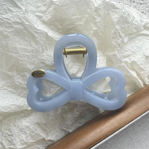 Detailed close-up of a handmade light blue bow hair claw clip with golden metal spring