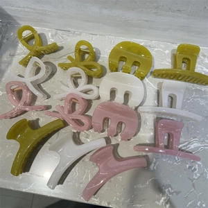 Flat lay of diverse French style M-shaped hair claws in olive green and ivory resin finish