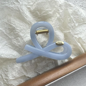 Detail of light blue resin hair claw clip with golden spring and Hand made tag
