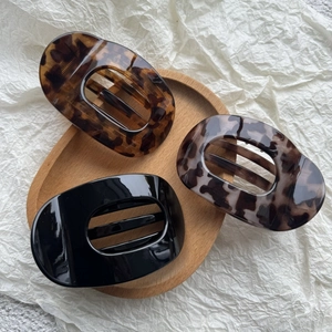 Detail view of acetate hair claws in amber, marble, and black finishes on a wooden tray
