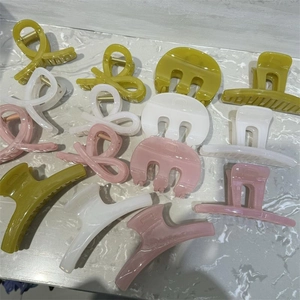 Close-up of assorted French style M-shaped hair claws in olive, rose, and white