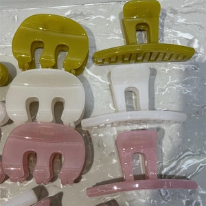 Detail view of M-shaped matte hair claws in avocado green, milk white, and bean paste pink