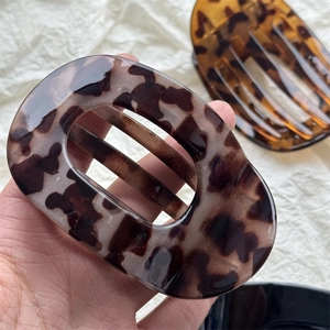 Detail of large acetate hair claw clip featuring classic dark amber leopard tortoiseshell pattern