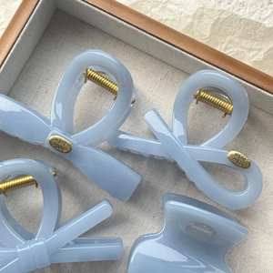 Close-up of matte blue bow-shaped acrylic hair clips with golden Handmade metal accents