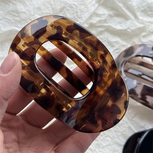 Classic tortoiseshell resin hair claw clip with hollow oval design for elegant styling