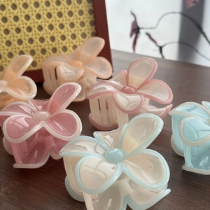 Pinces à cheveux élégantes en forme de fleurs aux tons pastel sur table en bois