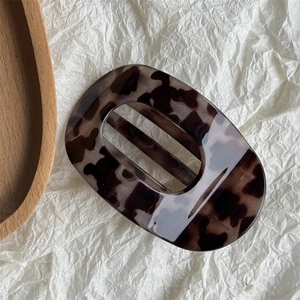 Detail view of tortoiseshell claw clip with acetate finish on white textured background
