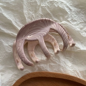Gros plan sur la texture marbrée d'une grande pince à cheveux rose et crème