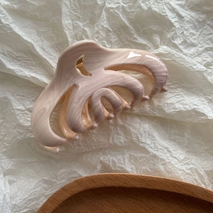 Détail d'une grande pince à cheveux en marbre rose et beige avec motif de vagues d'eau
