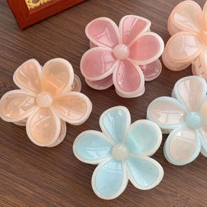 Lot de cinq pinces à cheveux fleurs en résine translucide sur une table en bois foncé