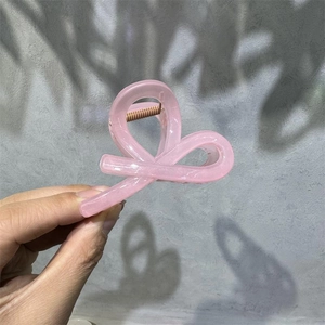 Close-up of a translucent pink French hair claw clip with a stylish bow design and spring