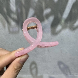 Detailed macro view of the pink acrylic M-shaped hair claw clip with marble texture