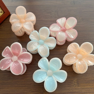 Mise à plat de six pinces à cheveux fleurs couleur macaron sur une surface en bois