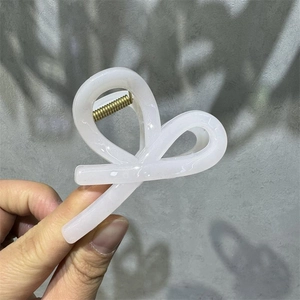 Detail of a light pink translucent M-shaped hair claw with gold metal spring