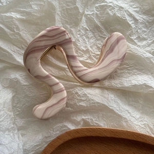 Détail de la pince à cheveux en S avec motif marbré rose violet et ressort doré