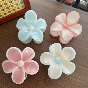 Vue détaillée de quatre pinces à cheveux florales en résine pastel sur bois sombre