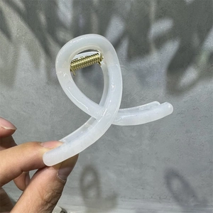 Detail of cream white hair claw clip with transparent finish and durable gold spring