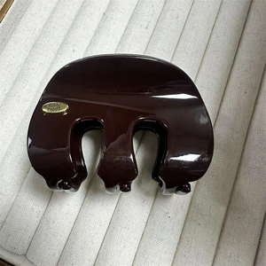 Vue détaillée de la pince à cheveux marron foncé avec logo métallique doré Hand Made