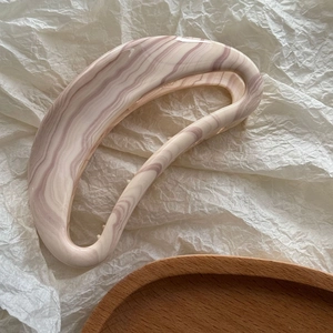 Détail d'une grande pince à cheveux en acétate avec texture marbrée crème et violette