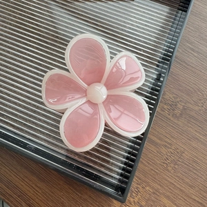 Détail d'une pince à cheveux fleur en résine rose avec des pétales semi-transparents