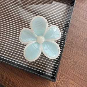 Détail de la pince à cheveux fleur bleu bonbon avec bordure blanche et centre arrondi