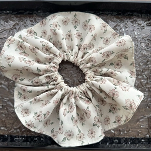Détail d'un chouchou géant en mousseline avec motif floral rose et feuilles vertes