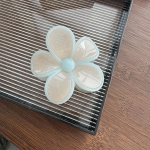 Détail d'une pince à cheveux fleurie aux tons pastel avec des pétales crème