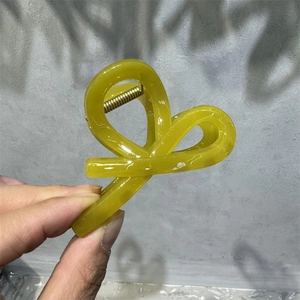 Detail view of large bright yellow translucent M-shaped hair claw clip with strong spring