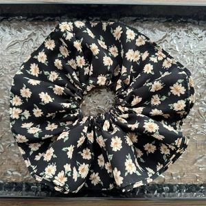 Détail d'un grand chouchou en mousseline noire à motif floral et couches de volants