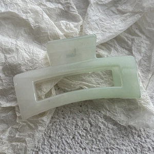 Gros plan d'une grande pince à cheveux carrée vert menthe avec paillettes sur papier blanc