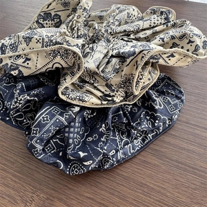 Floral paisley fabric hair scrunchies set in beige and navy blue on a wooden desk