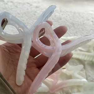 Détail de grandes pinces à cheveux étoile de mer en résine avec fini mat rose et blanc