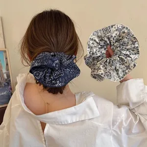 Detail of blue and beige paisley printed satin scrunchies with soft texture and rich patterns