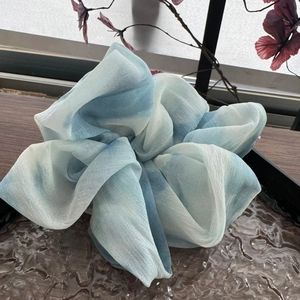 Dettaglio di un elastico in chiffon blu e bianco con trama sfumata su un tavolo