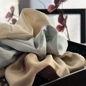 Detailansicht großer Satin-Haargummis in Creme, Blau und Gold mit seidiger Textur